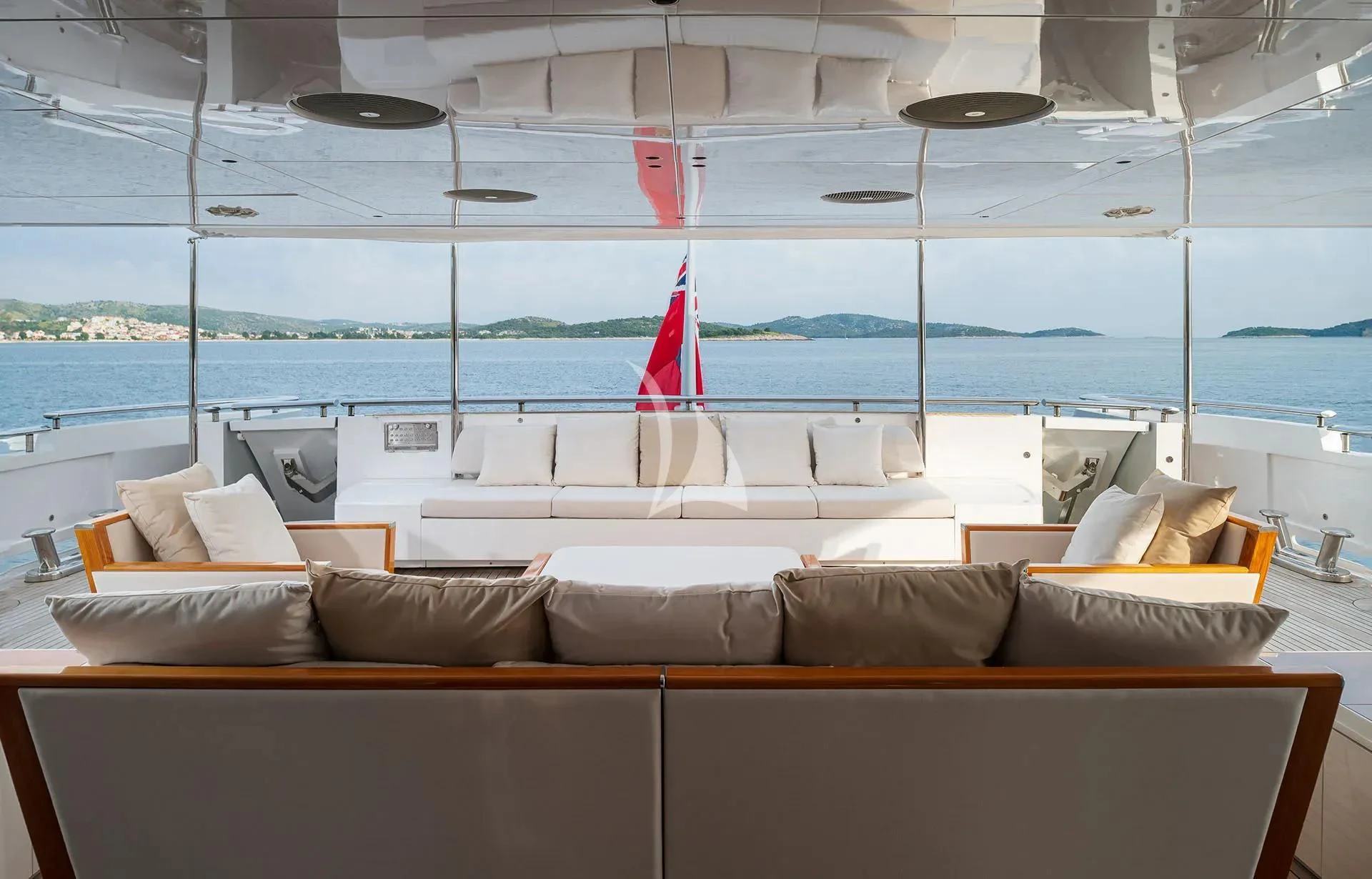 a lounge area with a large sofa and a large window with a sailboat in the background aboard TALEYA Yacht for Sale