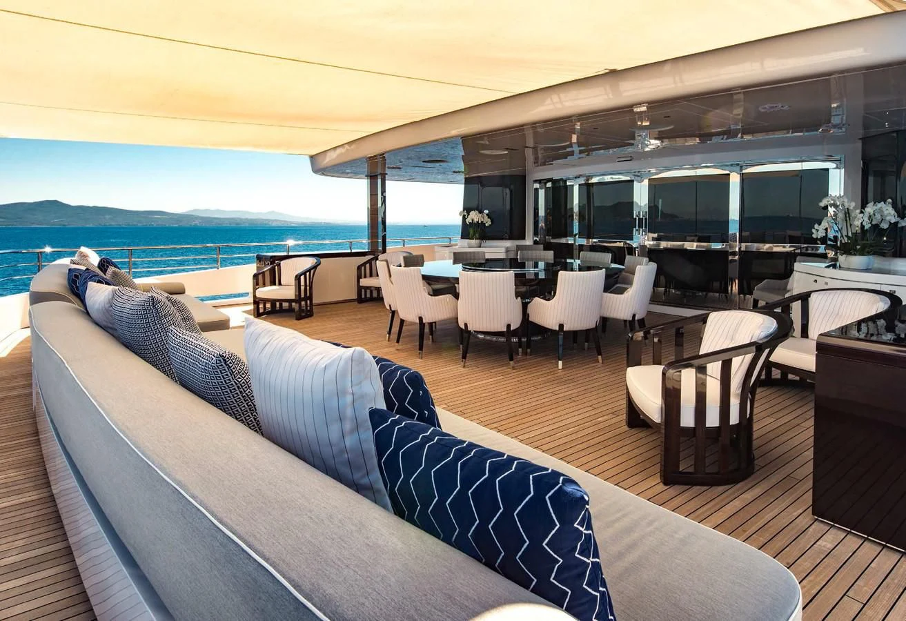 a large lounge area with a large blue sofa and a large window overlooking a large body of water aboard TALEYA Yacht for Sale