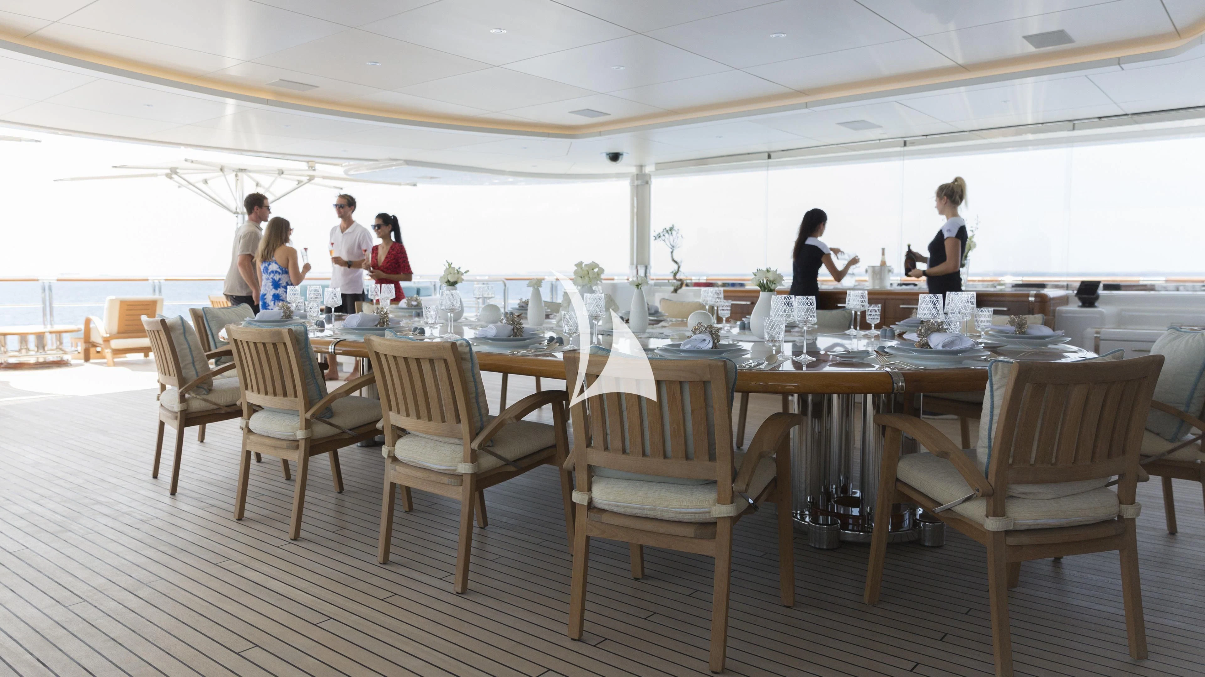 a group of people standing around a table with chairs aboard NIRVANA Yacht for Sale