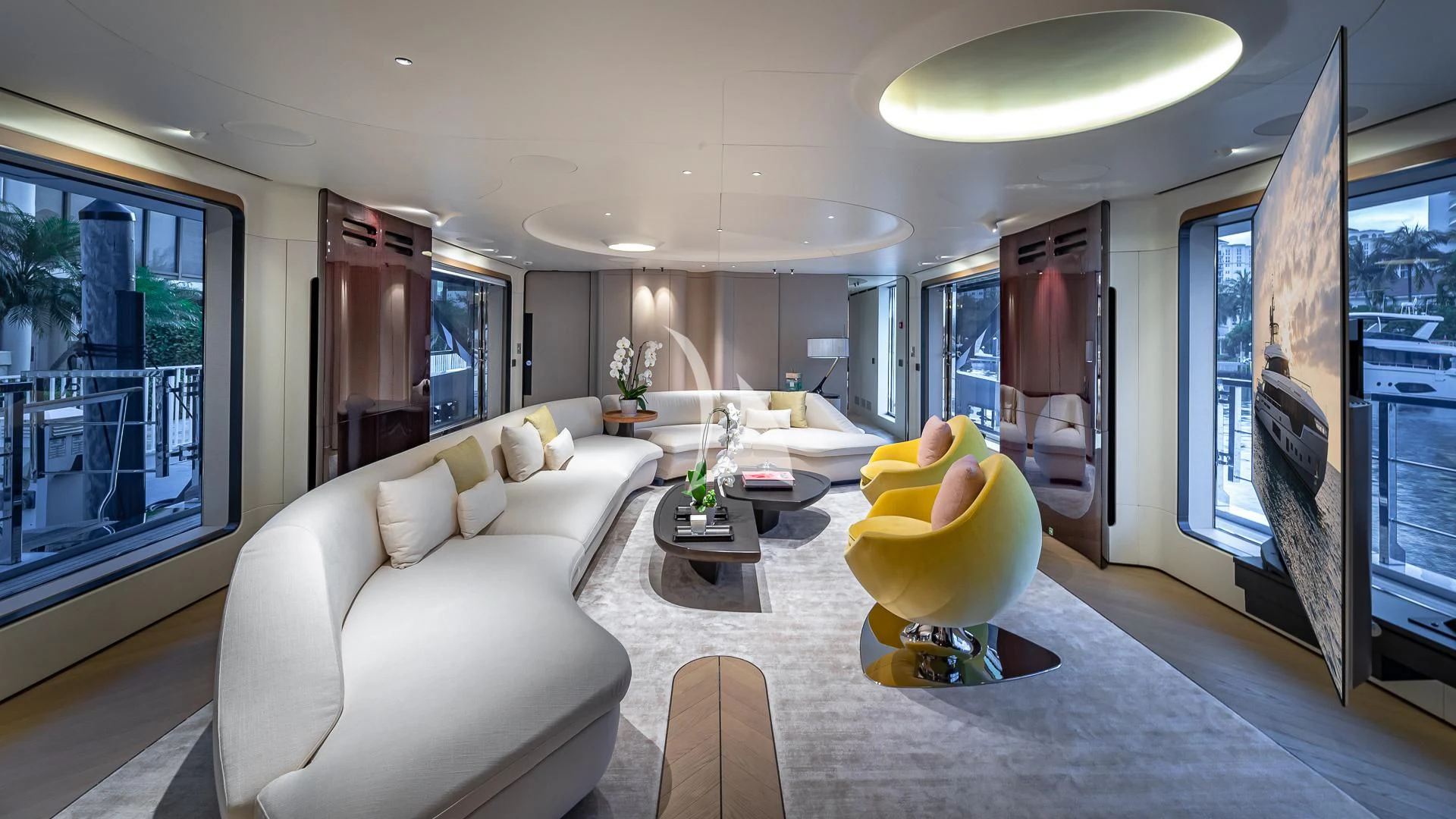 a living room with a large white couch and a large window aboard VOLO MARE Yacht for Charter