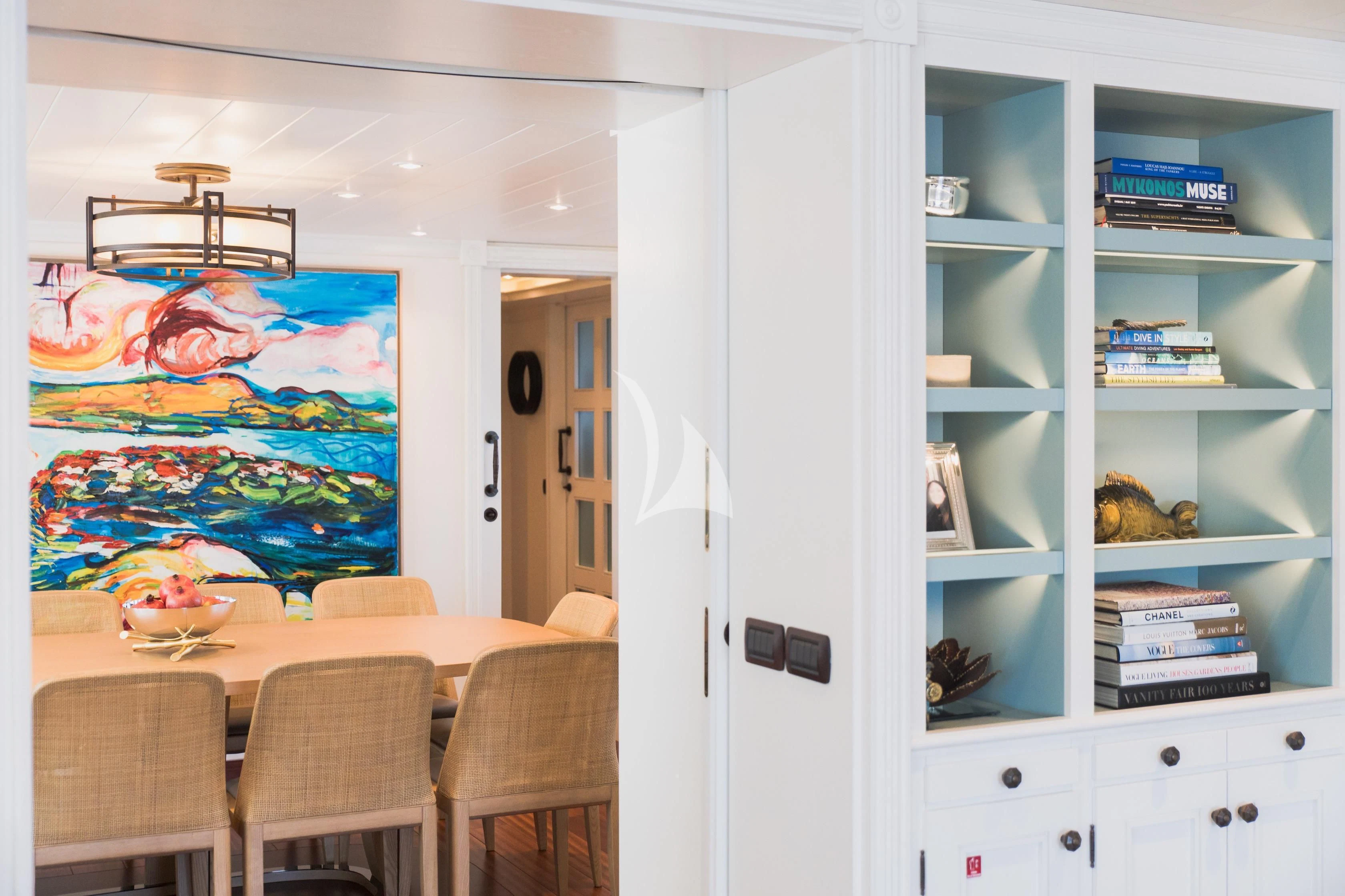 a room with white cabinets and a table with a shelf with books on it aboard LADY TRUDY Yacht for Charter