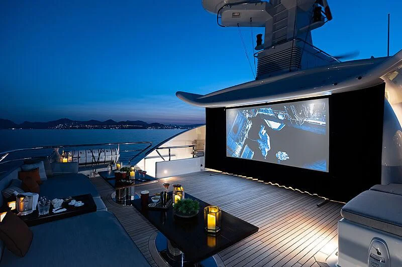 a large flat screen television on a deck overlooking a large body of water aboard LIND Yacht for Charter