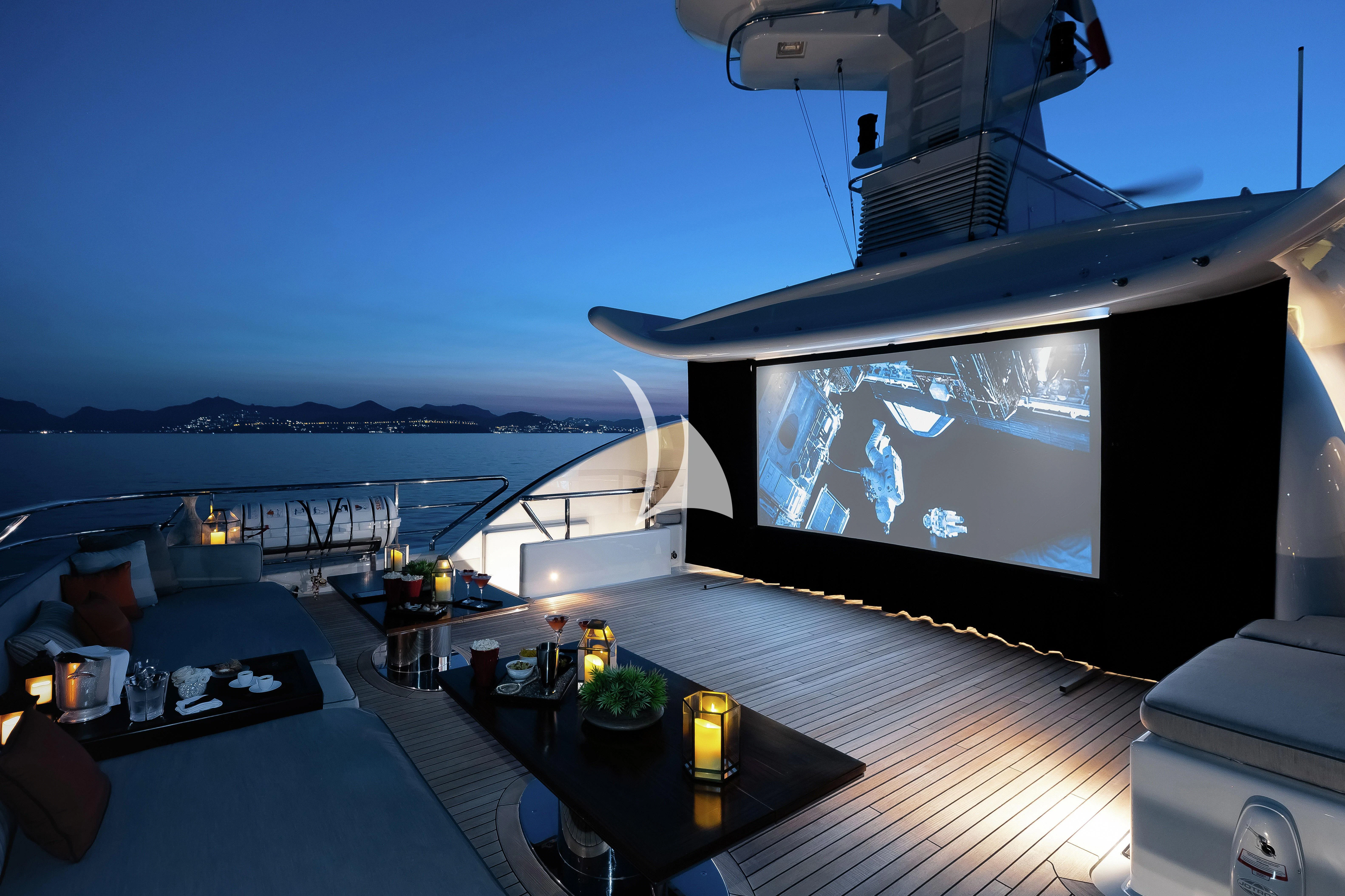 a large flat screen television on a wooden table next to a large body of water aboard LIND Yacht for Charter