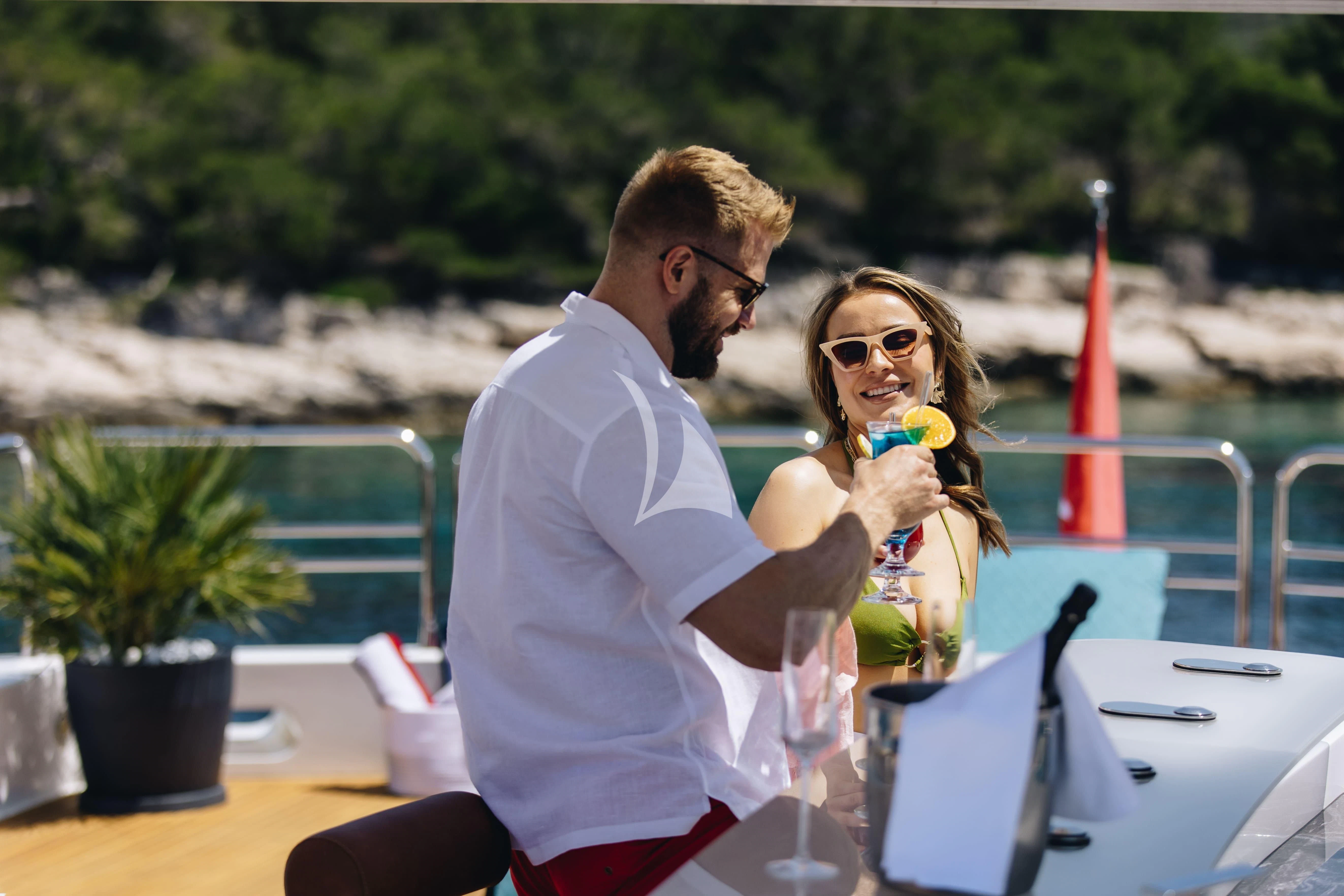 a man and woman sitting at a table with a flower in their hand aboard KATARIINA I Yacht for Sale