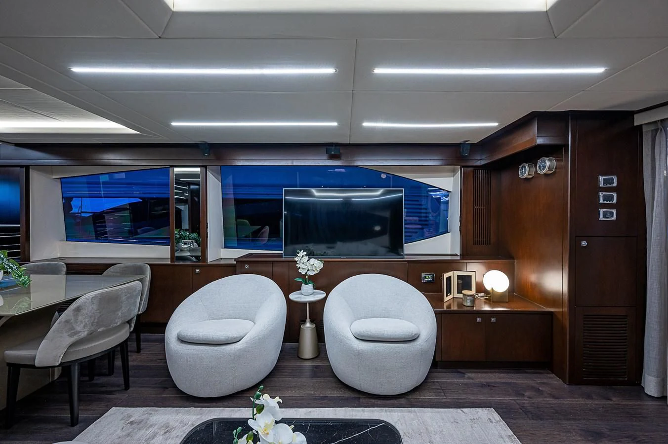 a room with a large television and a table with chairs aboard MOZZ II Yacht for Sale