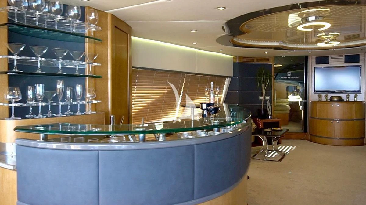 a room with a television and wine glasses aboard OBSIDIAN Yacht for Sale