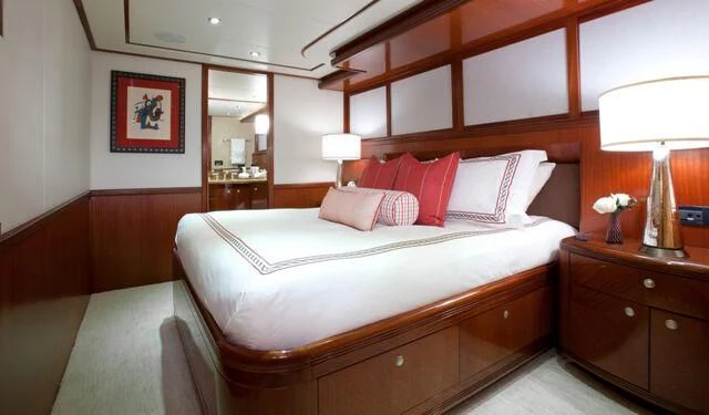 a bed with a white pillow and pink pillows aboard JUST ENOUGH Yacht for Charter