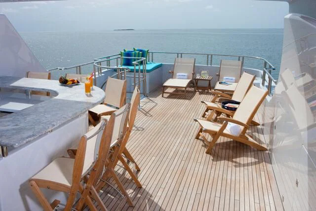 a deck with chairs and a table on it aboard JUST ENOUGH Yacht for Charter