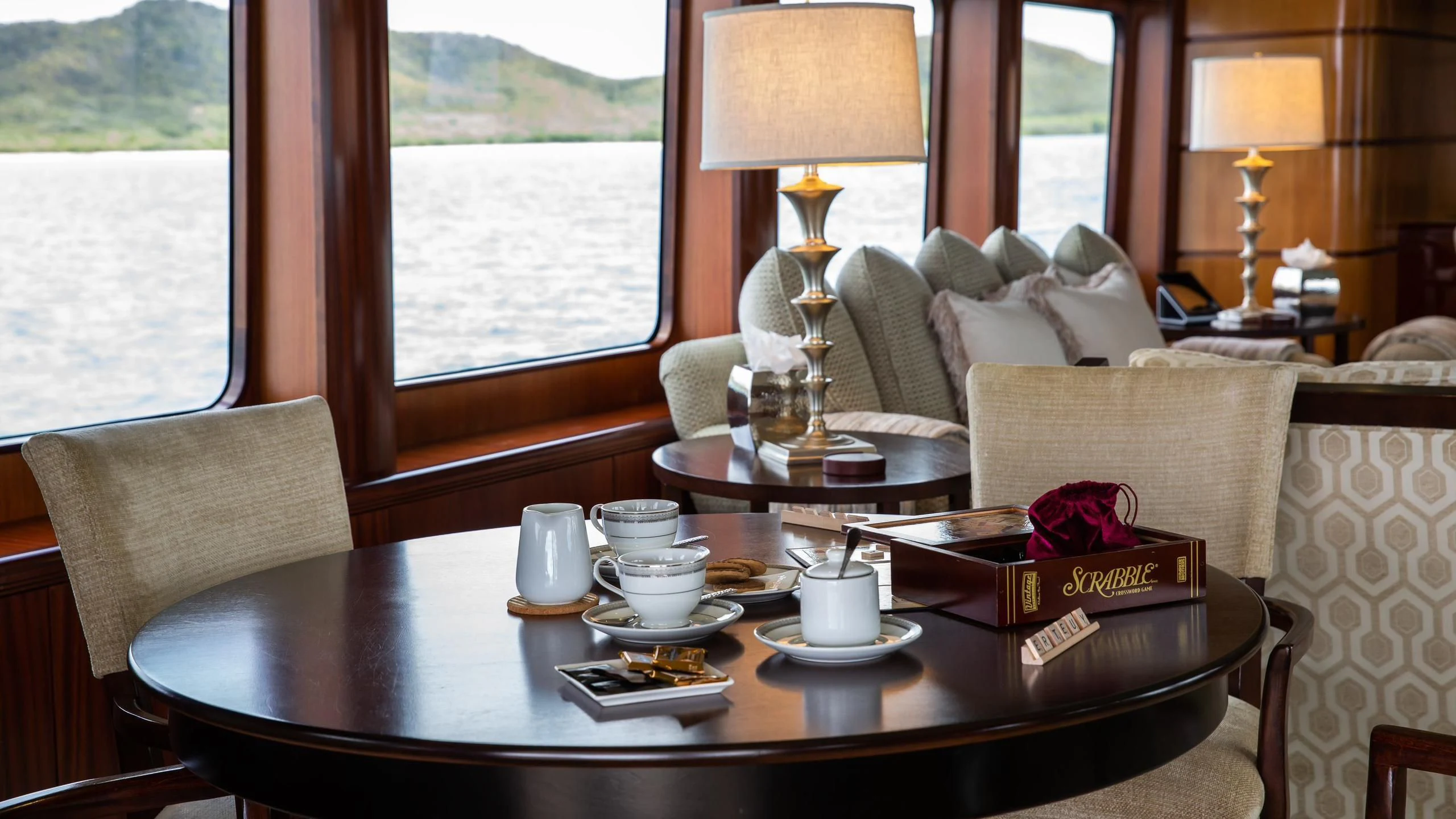 a table with a lamp and a couch by a window aboard JUST ENOUGH Yacht for Charter