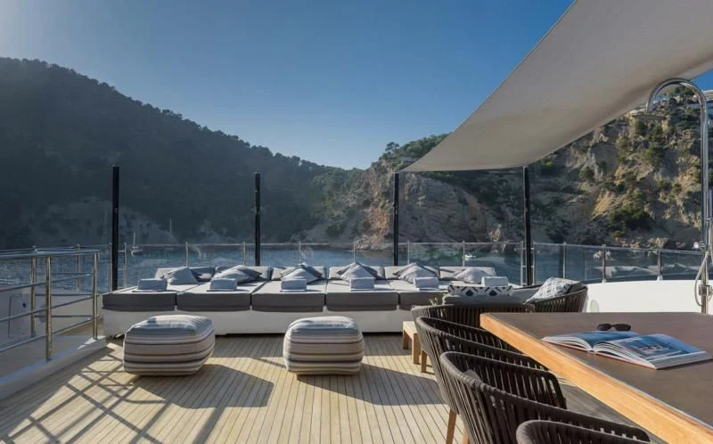 a deck with a view of a body of water and mountains aboard MR. T Yacht for Charter