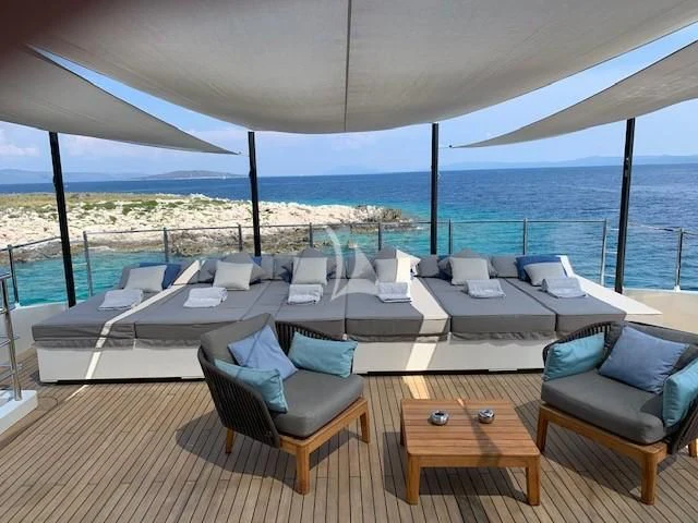 a room with a table chairs and a large body of water aboard MR. T Yacht for Charter
