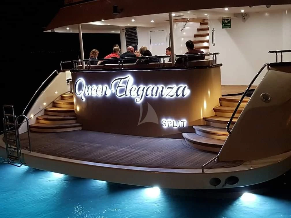 a group of people sitting in a room with a sign on the wall aboard QUEEN ELEGANZA Yacht for Sale