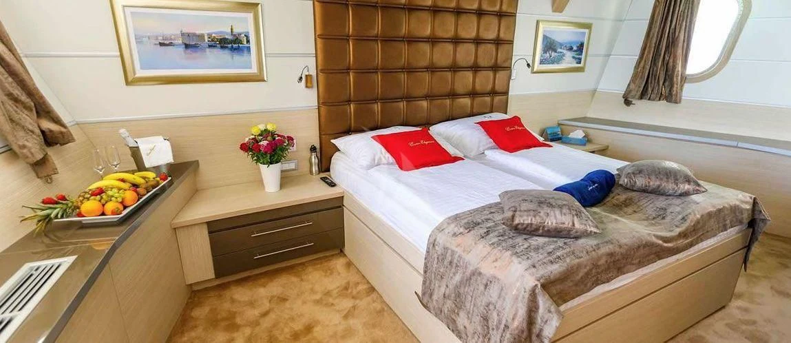 a bed with a tray of fruit on it aboard QUEEN ELEGANZA Yacht for Sale