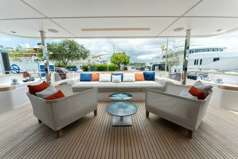 a living room with a large white sofa and a large boat in the background aboard OFFICIAL PLAN Yacht for Sale