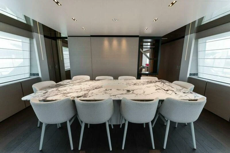 a large dining table with white chairs aboard OFFICIAL PLAN Yacht for Sale