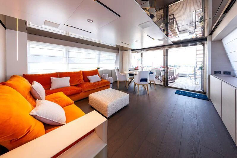 an open living room with orange couches and a large window aboard OFFICIAL PLAN Yacht for Sale