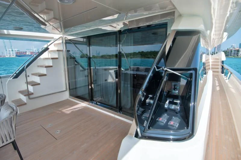 a room with a glass wall and a balcony with a view of the water and a city aboard CIAO II Yacht for Sale