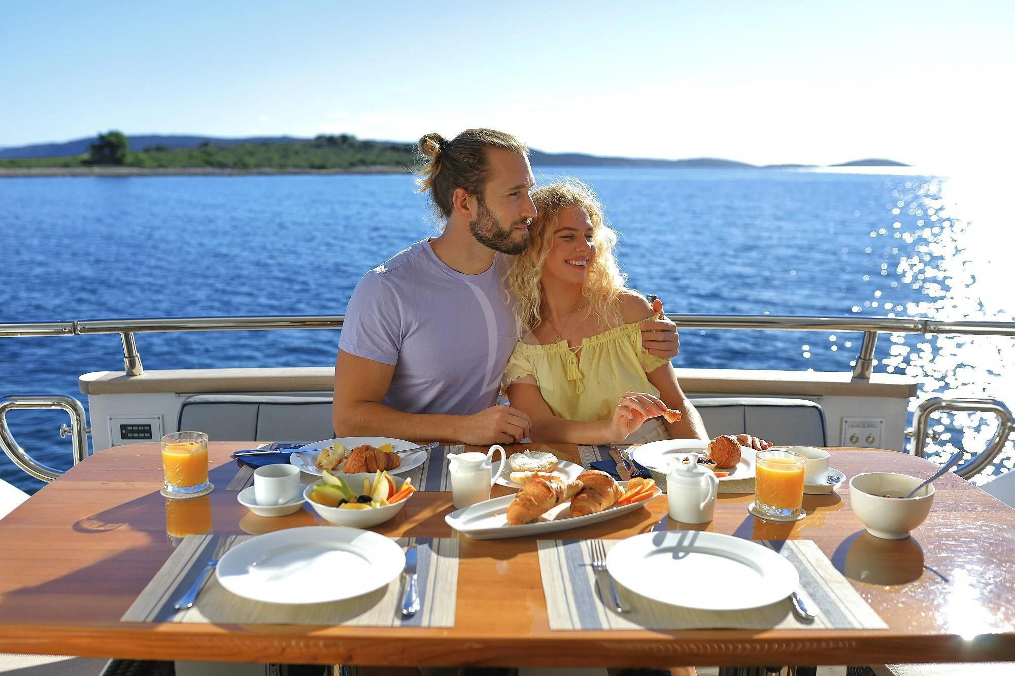 a man and woman sitting at a table with food and drinks on it aboard HOPE I Yacht for Charter