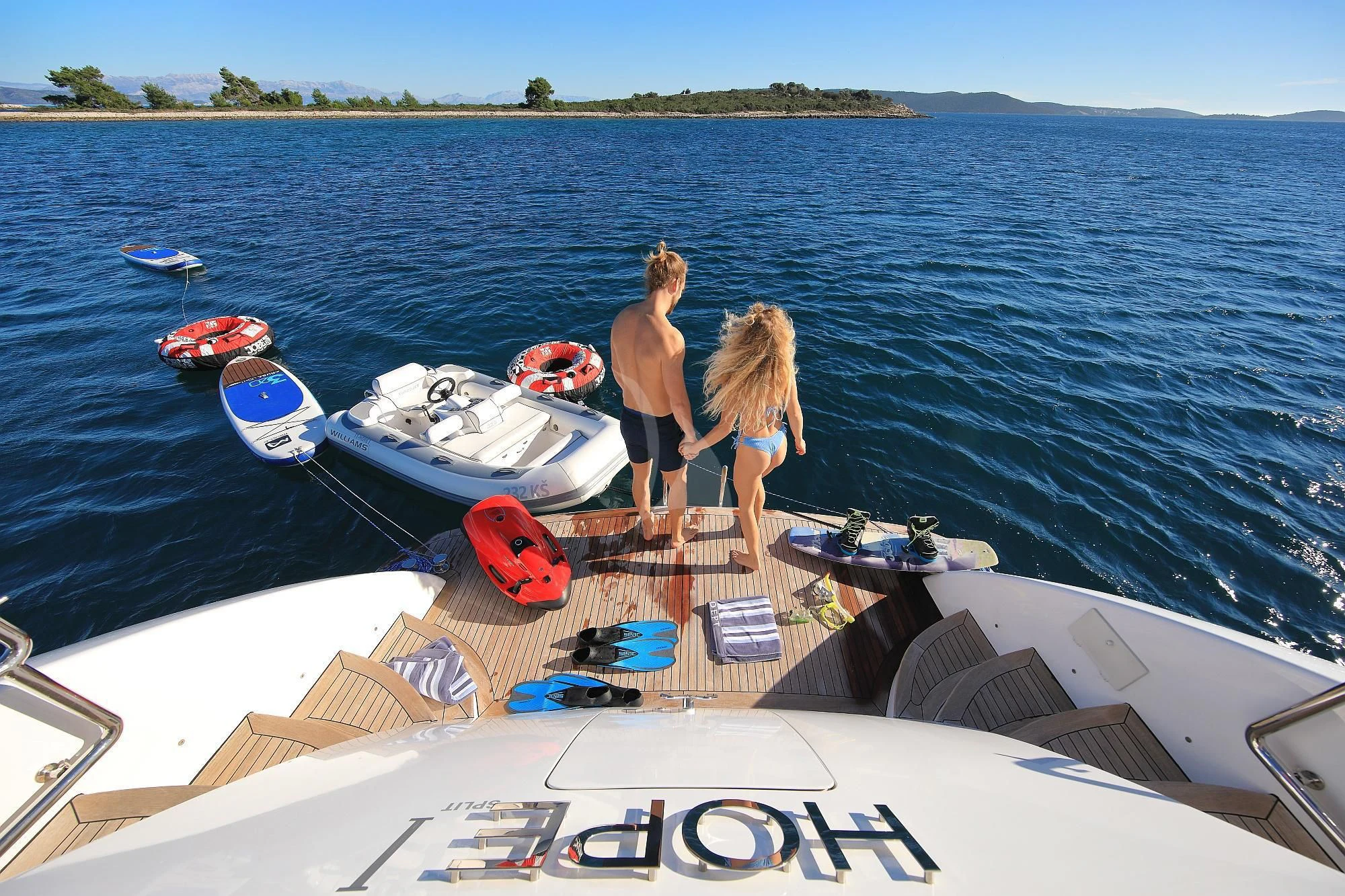a man and woman standing on a boat with a woman standing on the side aboard HOPE I Yacht for Charter