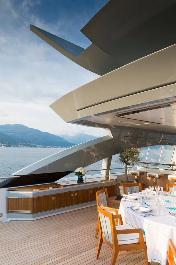 a deck with a table and chairs on it and a body of water in the background aboard GAJA Yacht for Sale