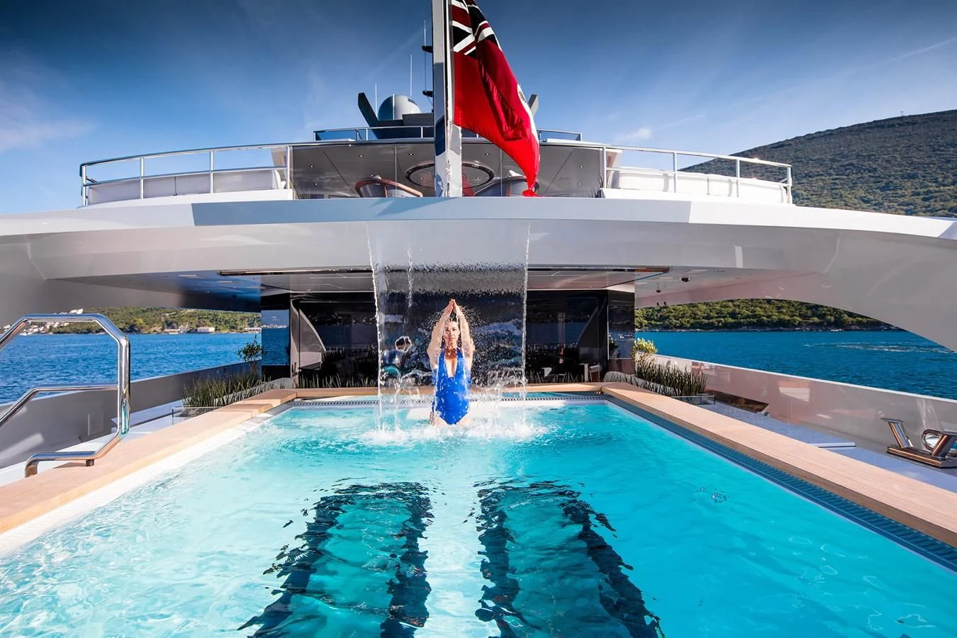 a large white building with a pool and a flag on the roof aboard GAJA Yacht for Sale