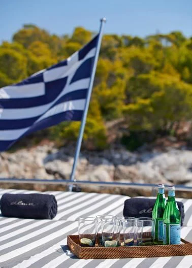 a picnic table with a flag and a bottle of wine aboard ALMA Yacht for Sale