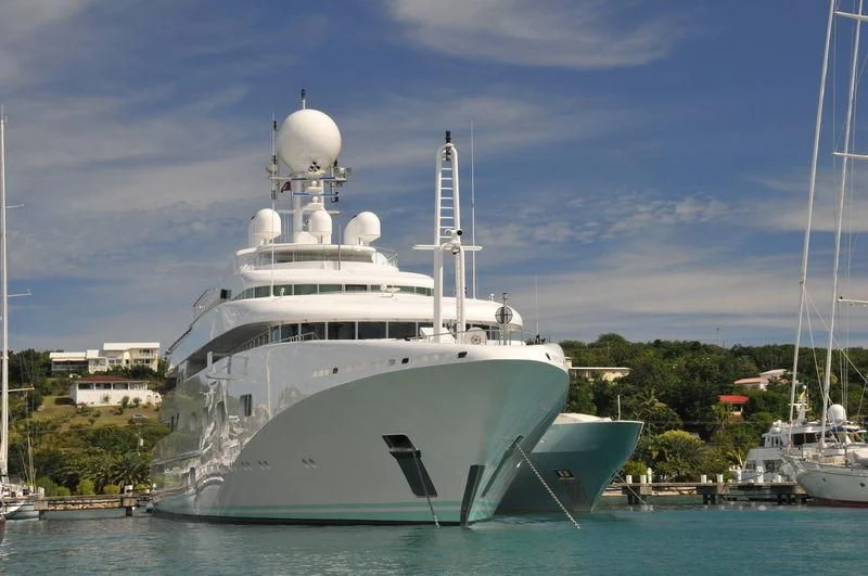 a large white boat in the water with Tengku Tengah Zaharah Mosque in the background aboard PEGASUS VIII Yacht for Sale