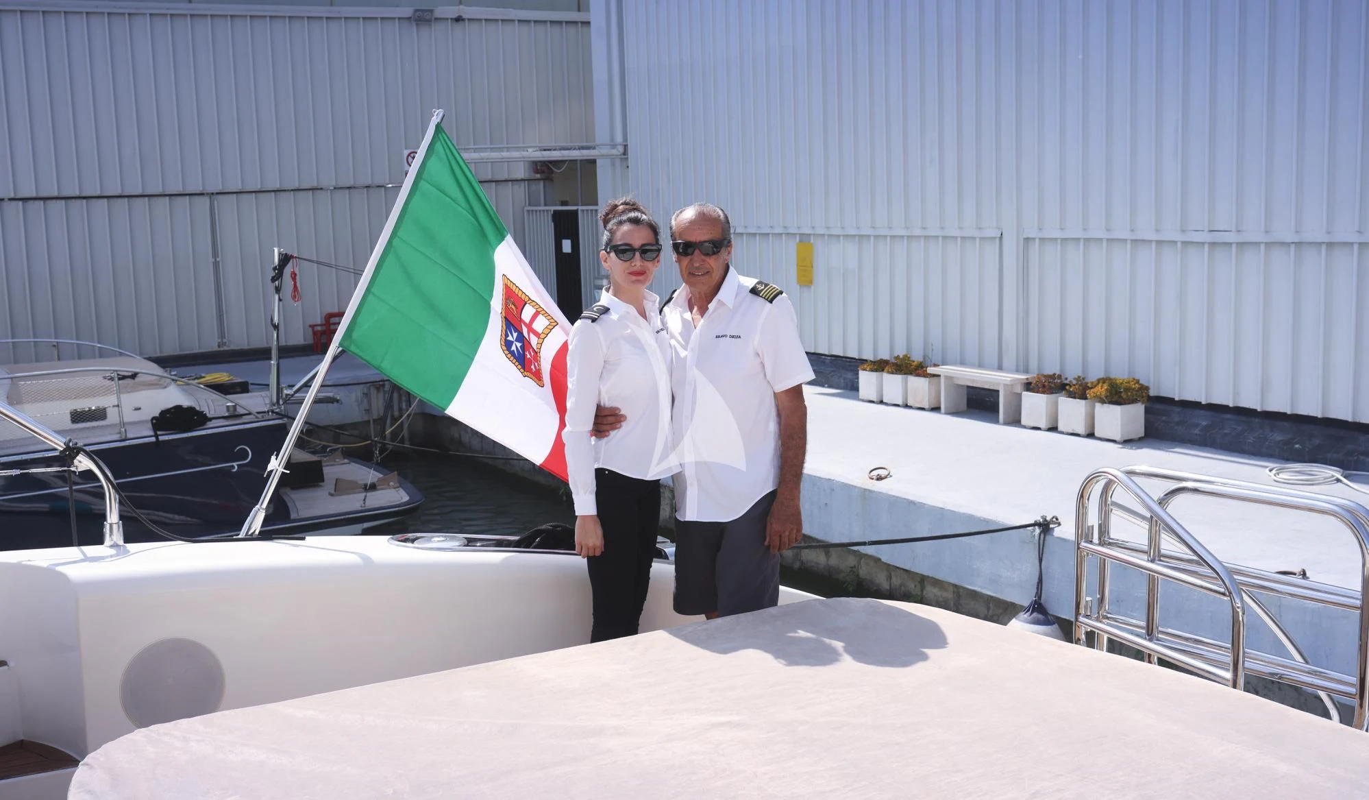 a man and woman standing next to a boat aboard BRAVO DELTA Yacht for Sale