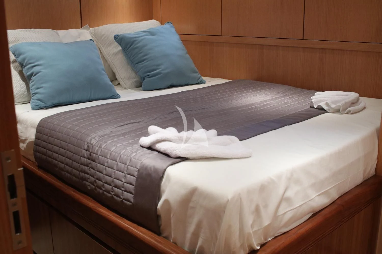 a bed with a white sheet and blue pillows aboard BRAVO DELTA Yacht for Sale