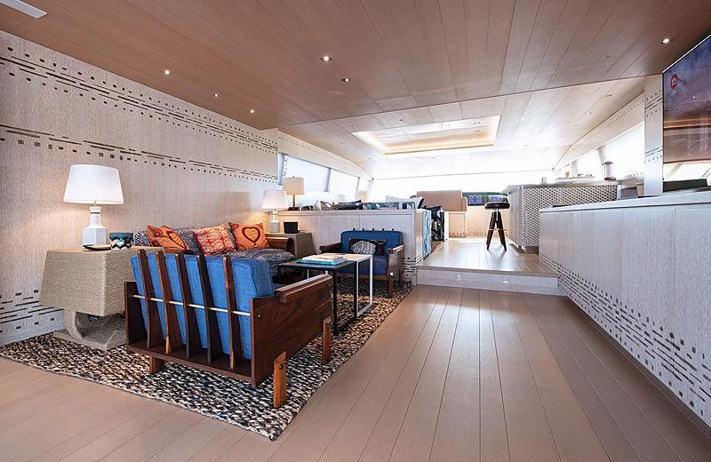 a large living room with a wood floor and a large blue couch aboard A2 Yacht for Sale