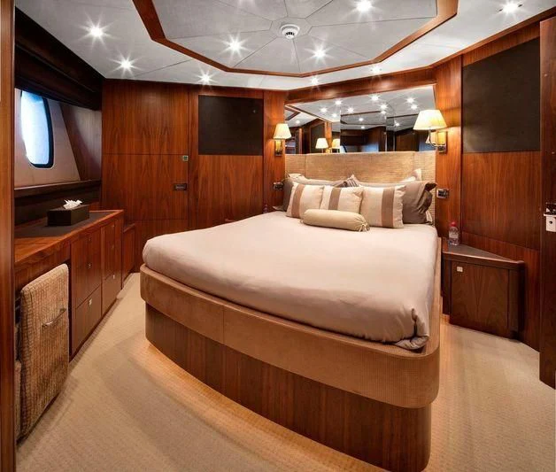 a bedroom with a bed and a wood cabinet aboard THE DEVOCEAN Yacht for Sale