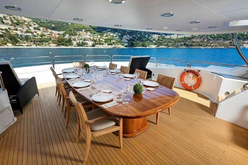 a dining table on a balcony overlooking a large pool aboard THE DEVOCEAN Yacht for Sale