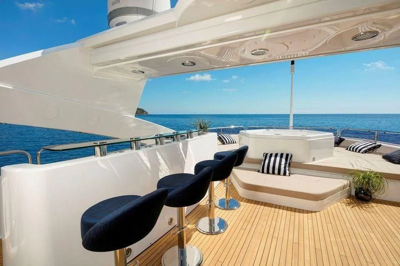 a room with a table and chairs on a deck overlooking the ocean aboard THE DEVOCEAN Yacht for Sale