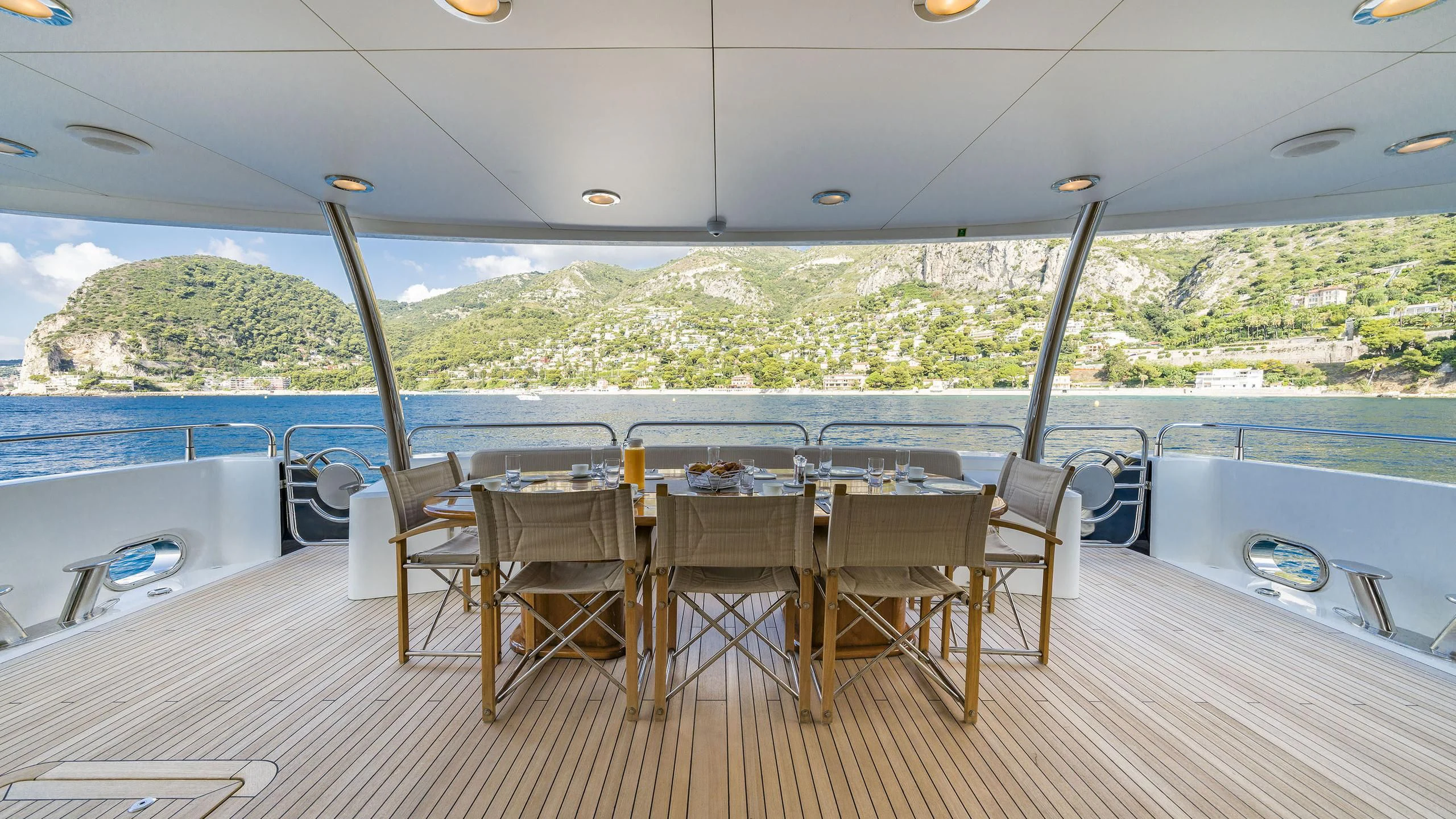a table set for a meal on a deck overlooking a large body of water aboard THE DEVOCEAN Yacht for Sale