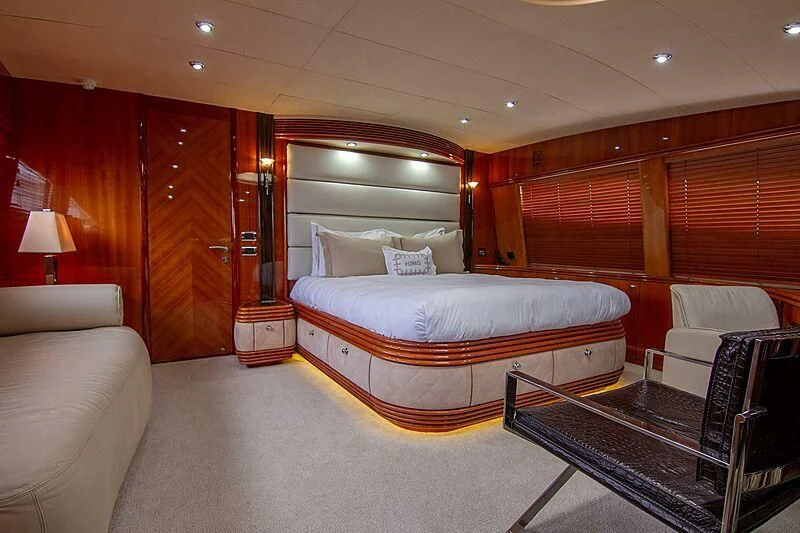 a large bedroom with a bed and a chair aboard #OMG Yacht for Sale