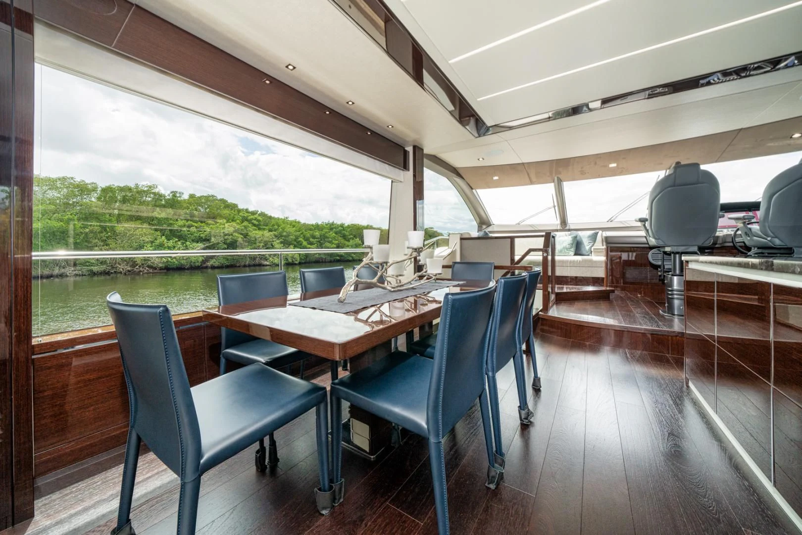 a wood table and chairs in a room with a wood deck and a large window with a view aboard TEMPUS FUGIT Yacht for Sale