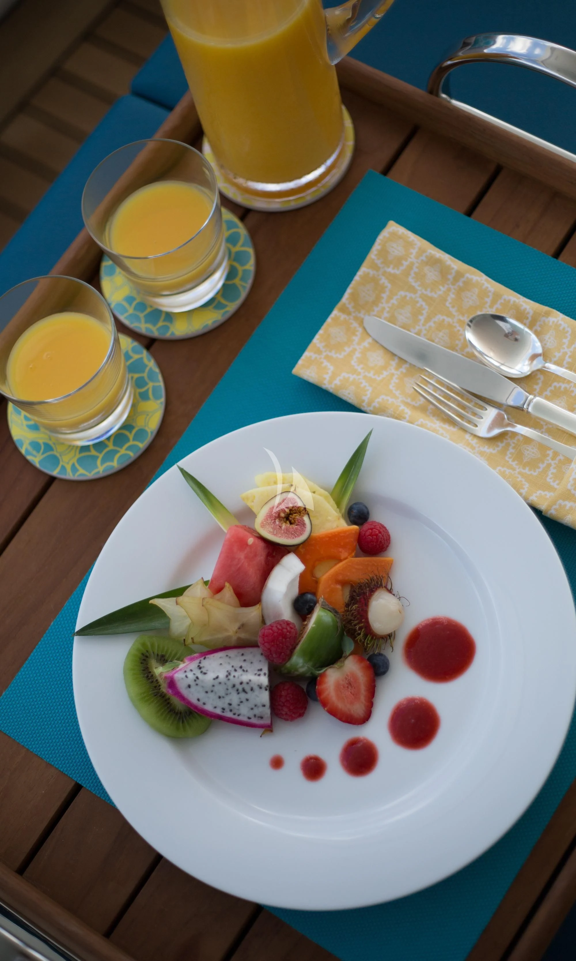a plate of food and a glass of juice on a table aboard DREAM Yacht for Sale