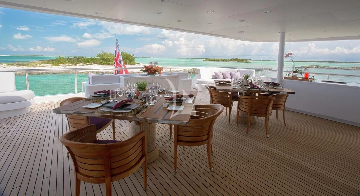 a table and chairs on a deck overlooking a body of water aboard DREAM Yacht for Sale