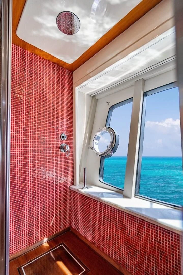 a room with a red wall and a window with a view of the water aboard INDULGE II Yacht for Sale
