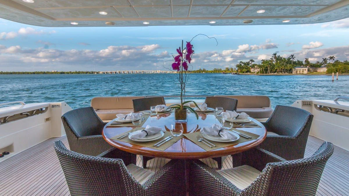 a table with chairs and a view of the ocean aboard INDULGE II Yacht for Sale