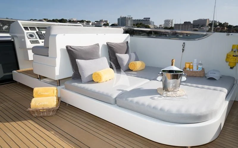 a large white bed with a white pillow and yellow pillows on it aboard CAROM Yacht for Sale