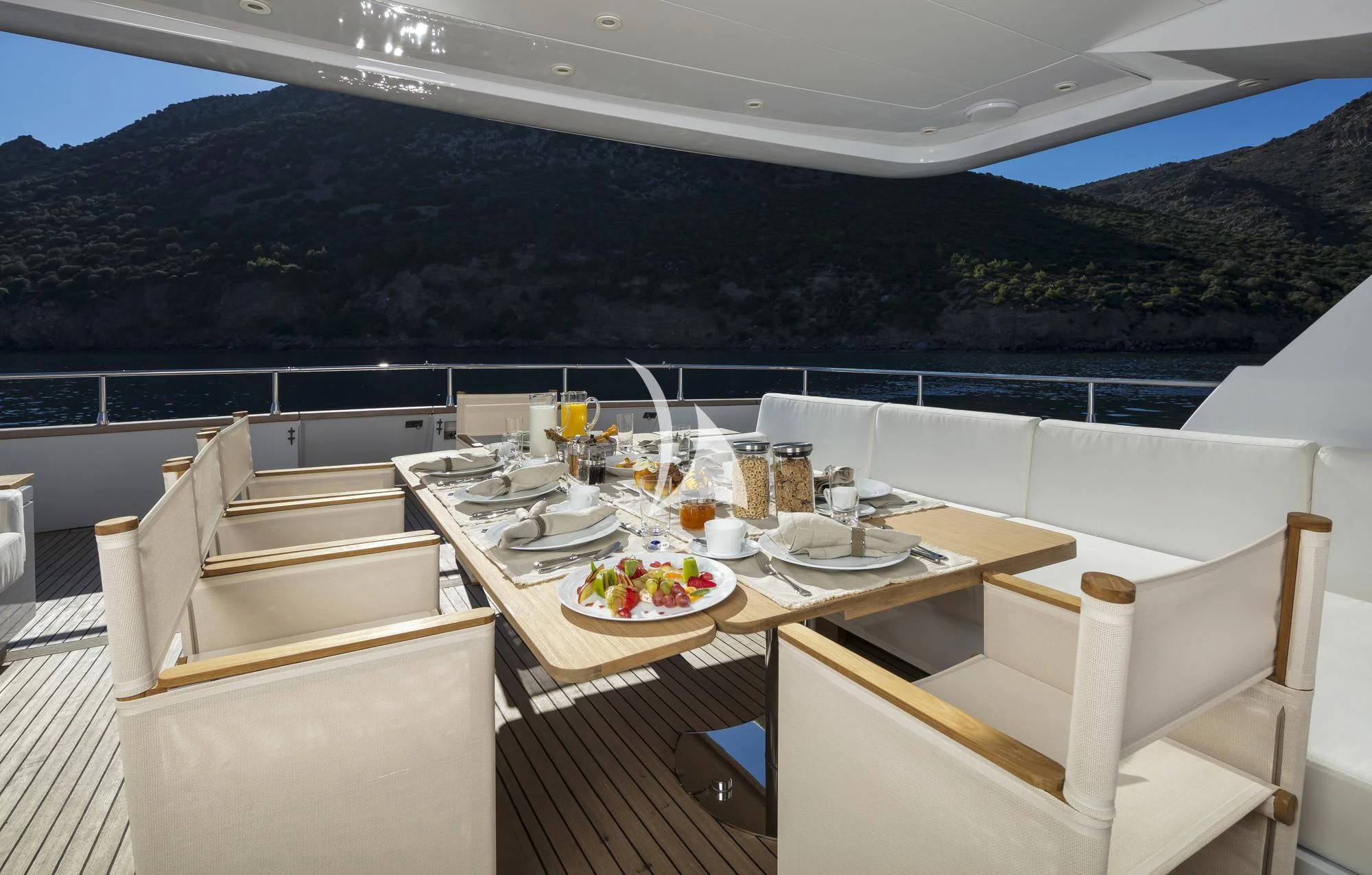 a table set for a meal on a balcony overlooking a mountain range aboard SOLE DI MARE Yacht for Sale