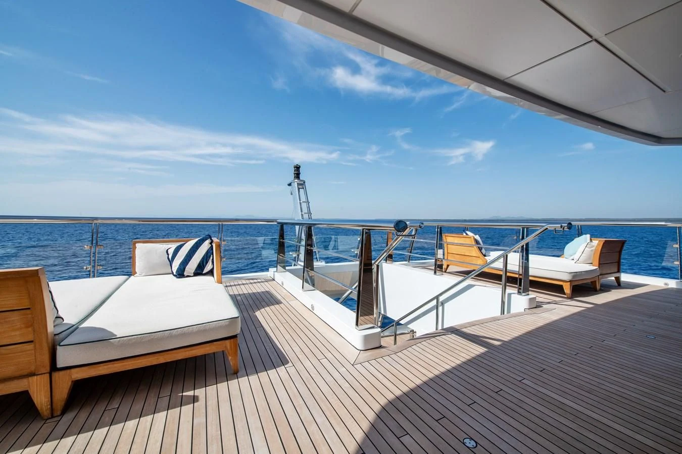 a deck with chairs and a body of water in the background aboard BATELLO Yacht for Sale