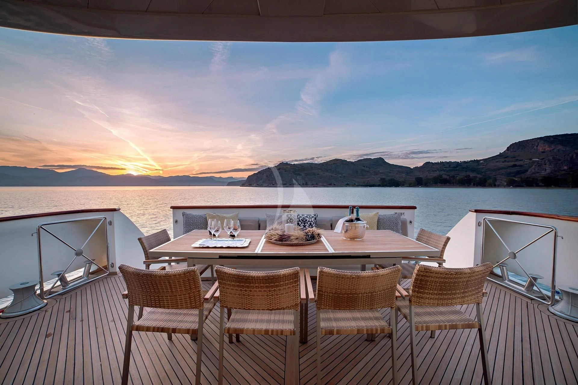 a table set for a meal on a deck overlooking a sunset aboard AQUILA Yacht for Sale