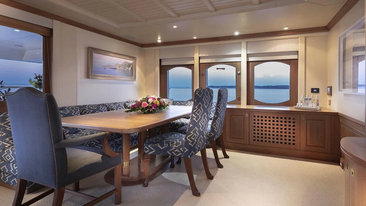 a dining table and chairs in a room with a large window aboard GLACIAL BEAR Yacht for Sale