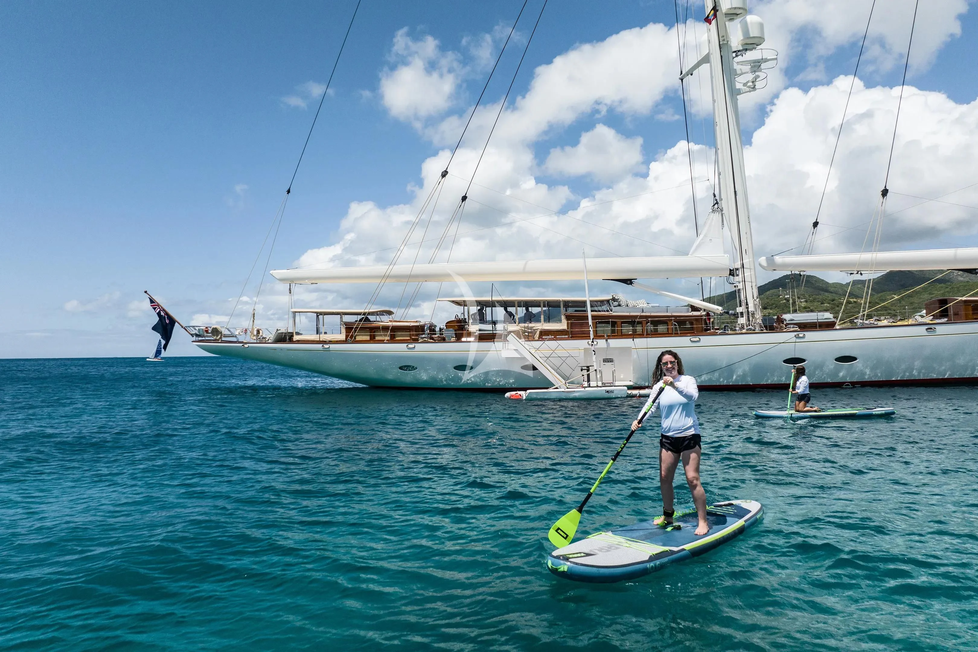 a person on a surfboard in the water with a sailboat in the background aboard ATHOS Yacht for Sale
