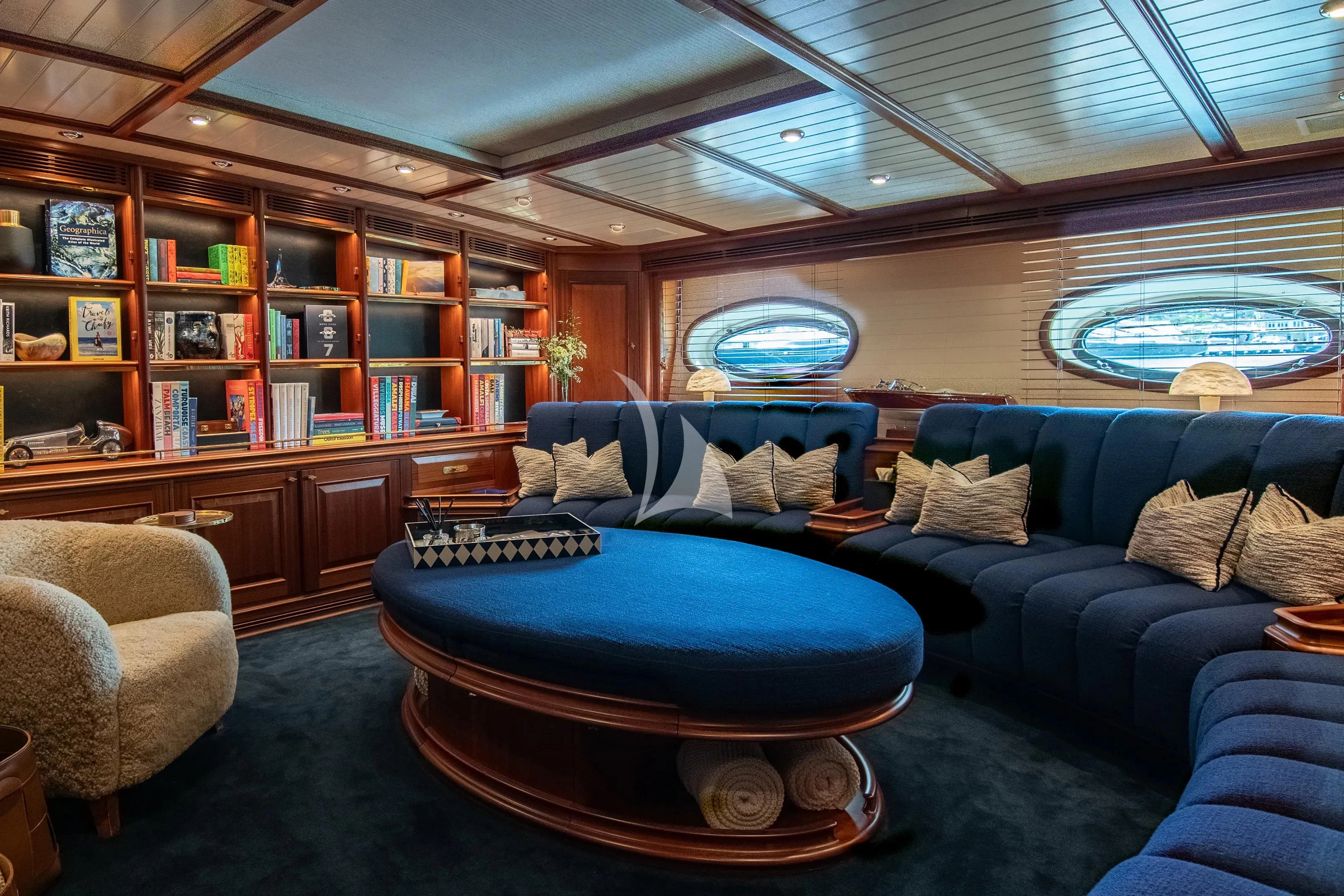 a living room with a large blue couch aboard ATHOS Yacht for Sale
