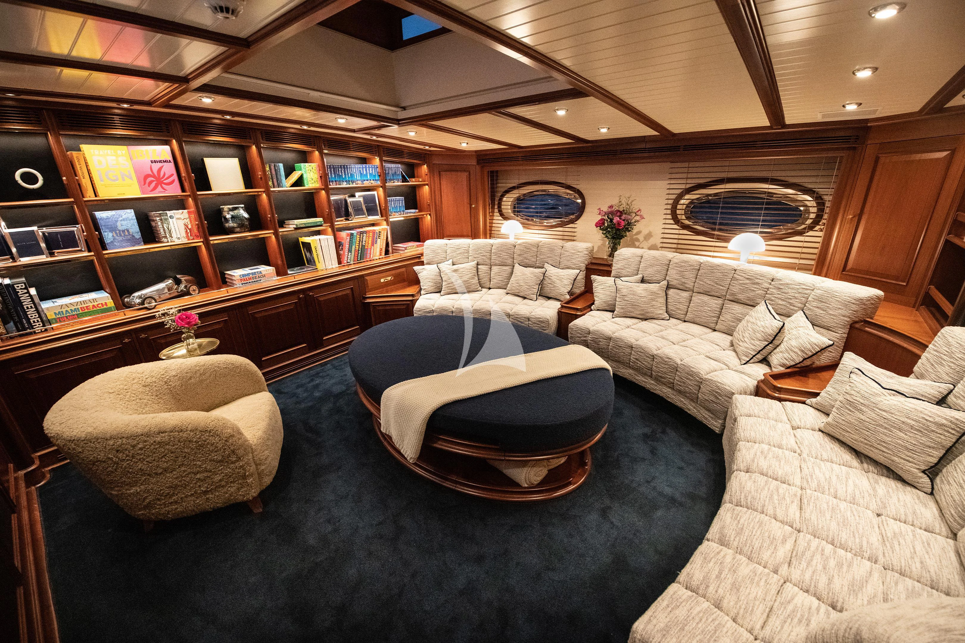 a living room with a large book shelf and couches aboard ATHOS Yacht for Sale