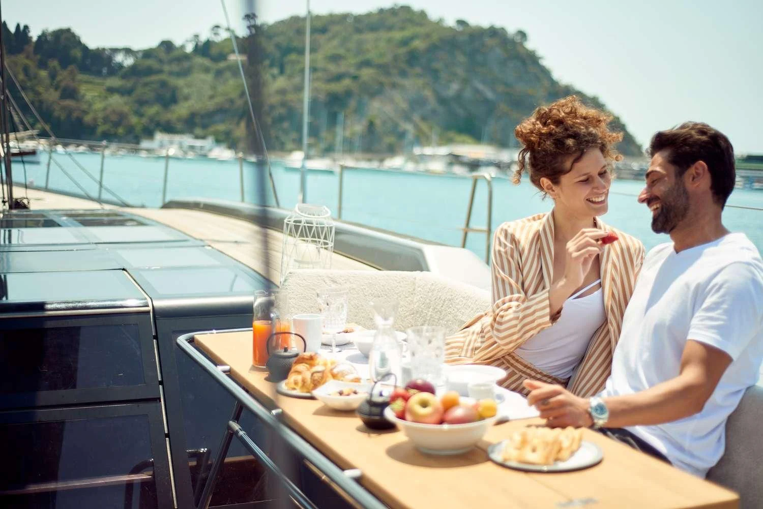 a man and a woman sitting at a table with food on it aboard AORI Yacht for Sale