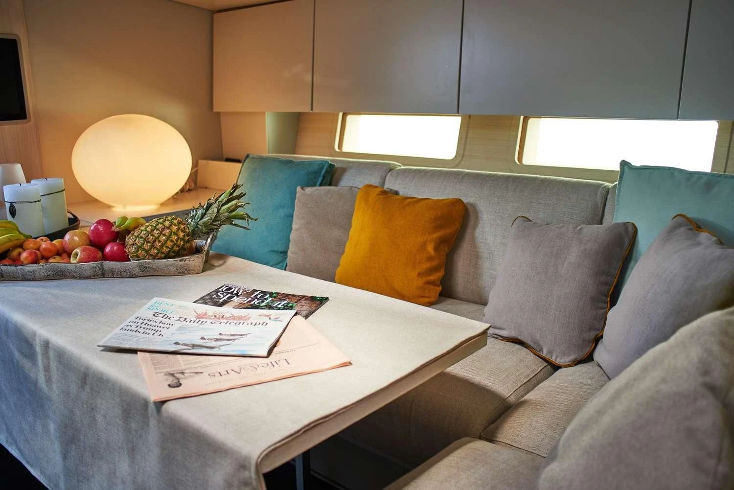 a couch and a table with fruits on it aboard AORI Yacht for Sale